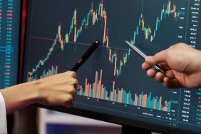 Cropped partners pointing by pen in stock market profit on computer. Infobahn.