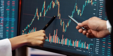 Cropped partners pointing by pen in stock market profit on computer. Infobahn.